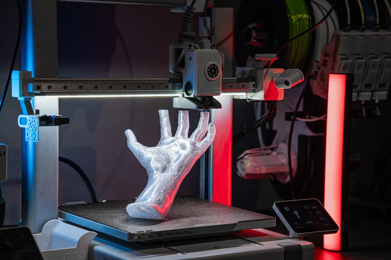Промисловий 3D-принтер під час друку деталі складної геометричної форми.