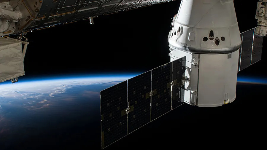 Вантажний корабель SpaceX Dragon пристикований до модуля Harmony МКС на тлі Землі